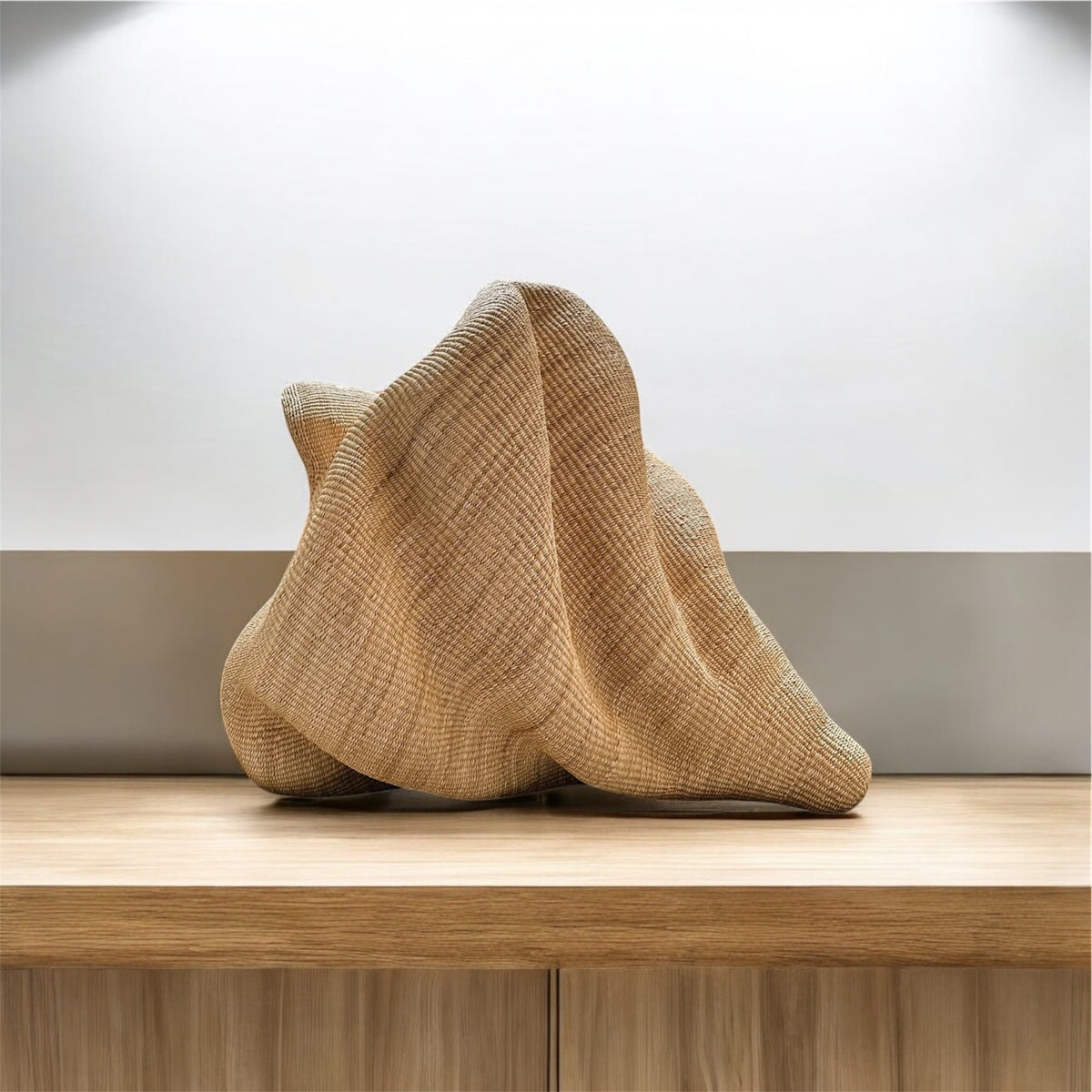 Sculptural woven natural-fiber piece on a wooden sideboard
