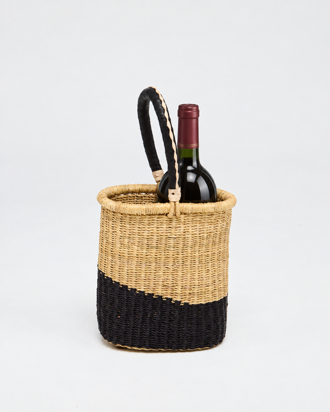 Woven bottle basket with a black leather handle, holding a bottle of wine