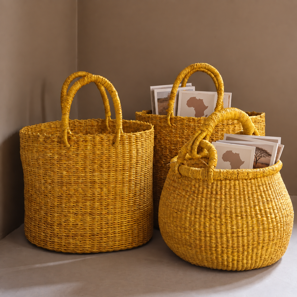 Three mustard-yellow woven baskets with handles, holding cards printed with a map of Africa